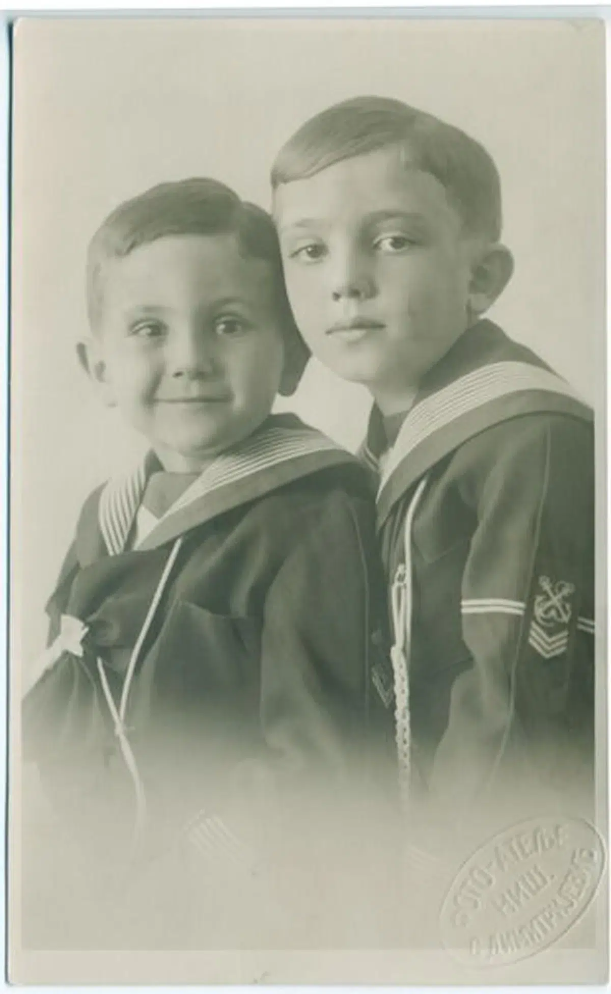 a vintage, sepia-toned portrait of two young brothers wearing matching sailor-style outfits