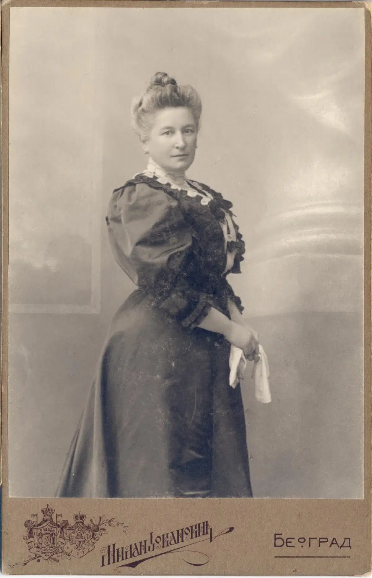 a faded, sepia-toned vintage studio photograph of a woman in a dark victorian dress, showing signs of aging and wear